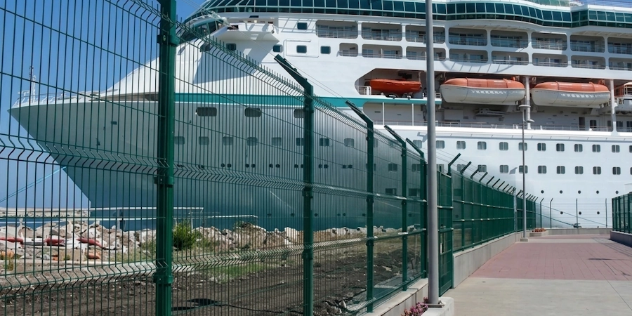 Reja DEACERO con acabado marino protegiendo el perímetro de un puerto, con un crucero al fondo